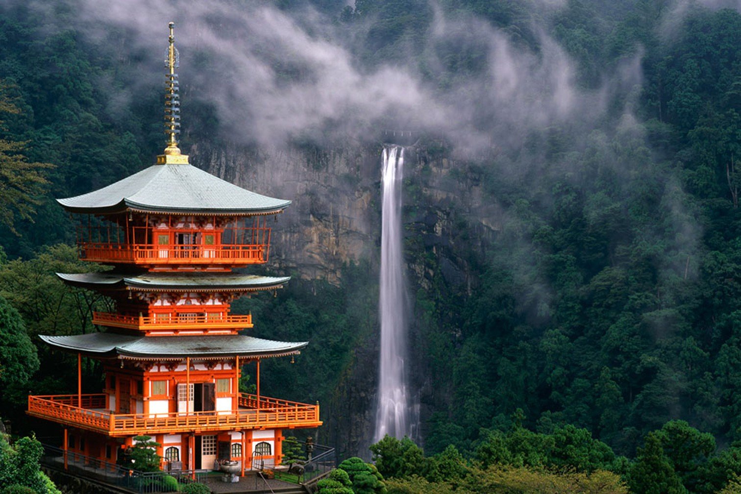 een rode pagoda met drie verdiepingen met op de achtergrond zocht op de hoogste waterval van Japan